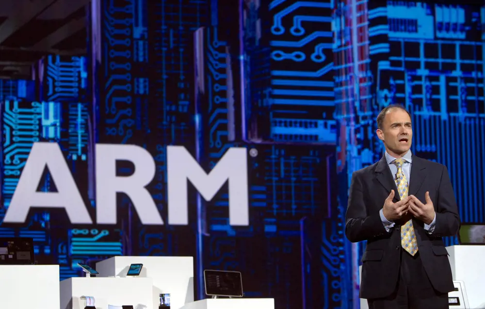 Warren East speaking at an event with the ARM logo in the background. 