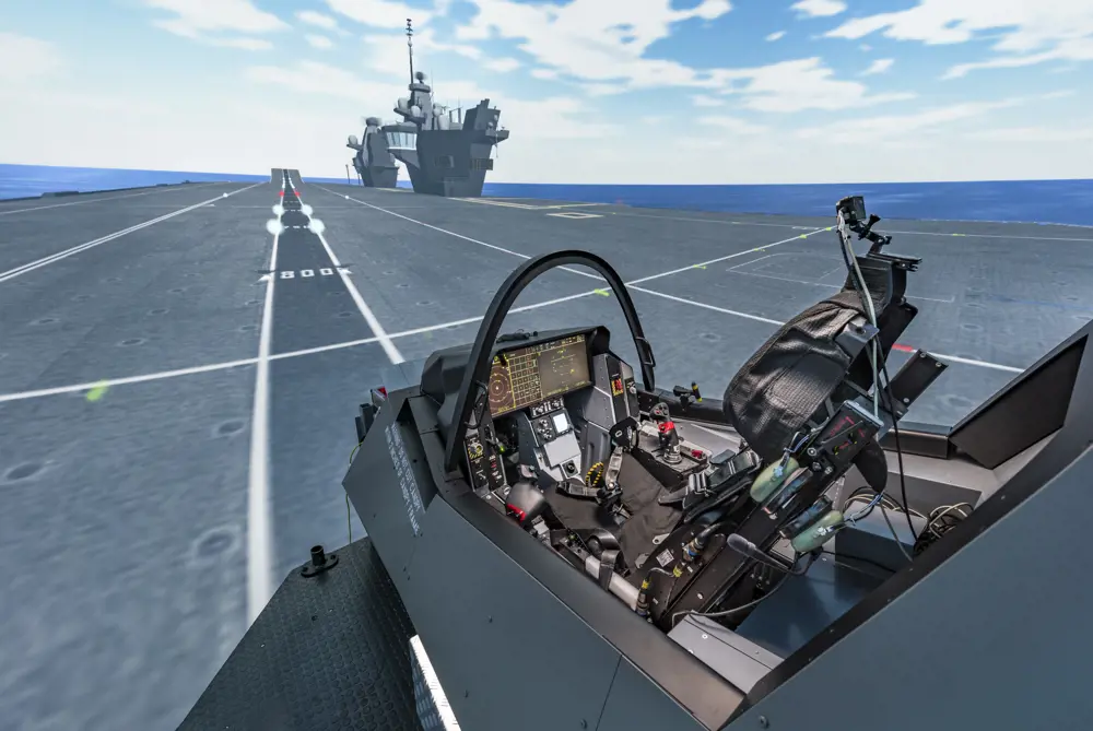 A view of the aircraft simulation showing the view from an empty pilot's seat at the back of a runway on a ship.