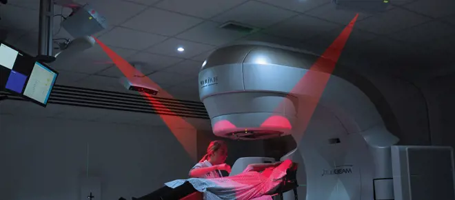A patient lying under a radiotherapy machine that is being used with the AlignRT system.