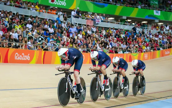 Four British Women's cyclists, cycling in a line in front of a crowd, in the velodrome at the Rio Olympics. 