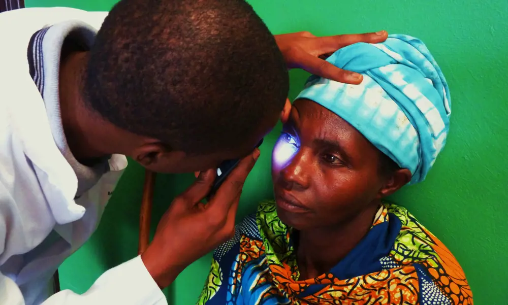 A doctor shining Arclight into a woman's eyes in Rwanda.