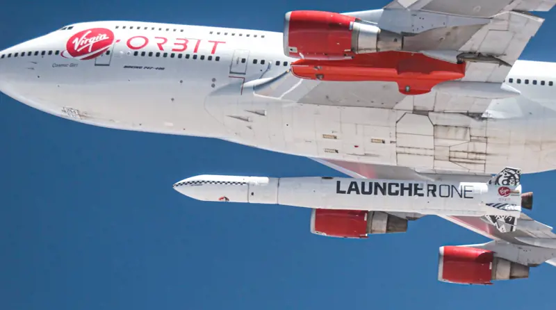 A view of the underside of the Cosmic Girl aircraft while it is in the air with the LauncherOne rocket attached underneath the aircraft wing. 