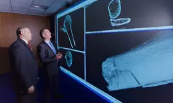 Professor Mark Williams and Detective Superintendent Mark Payne examining 3D scans of bones on a large screen.
