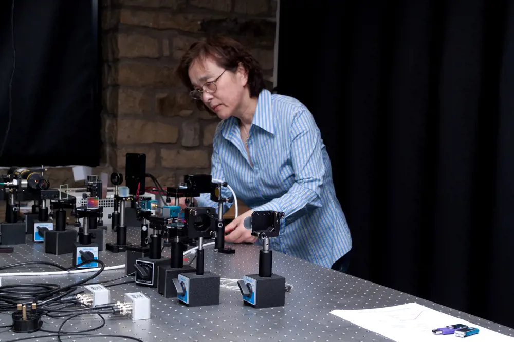 Professor Jane Jiang adjusting the setup of optical apparatus on an optical workbench. 