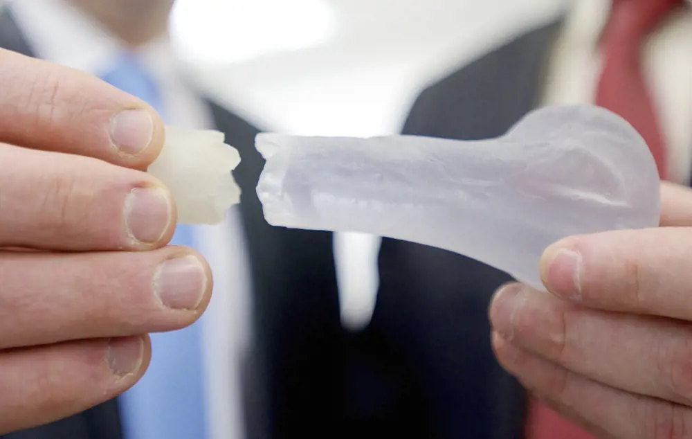 Two hands holding each part of a 3D printed fractured bone.