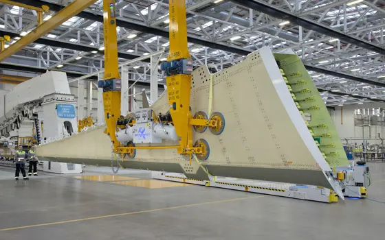 The inside of a factory with an aircraft wing being being lifted from a jig in Belfast.