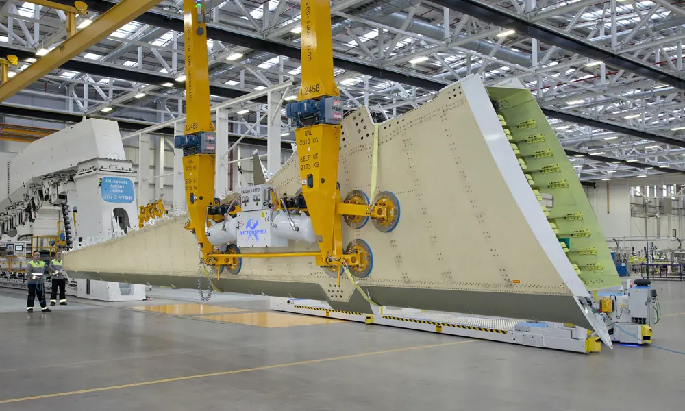 The inside of a factory with an aircraft wing being being lifted from a jig in Belfast.