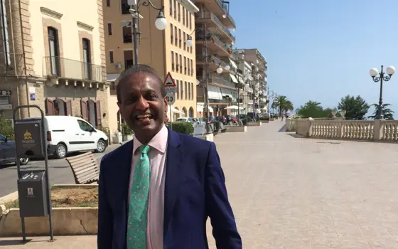 Dr Rajapillai (RV) Ahilan on a sunny beachside promenade in Italy.