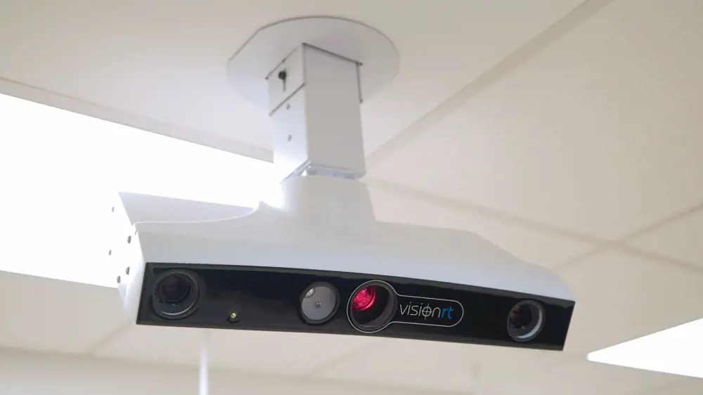 The visionRT laser projector and camera hanging from a ceiling. 
