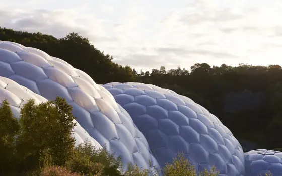 The plastic covered geodesic domes of the Eden Project seen below a bright but cloudy sky.