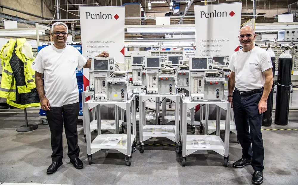 Two engineers standing either side of a VCUK ventilator prototype.