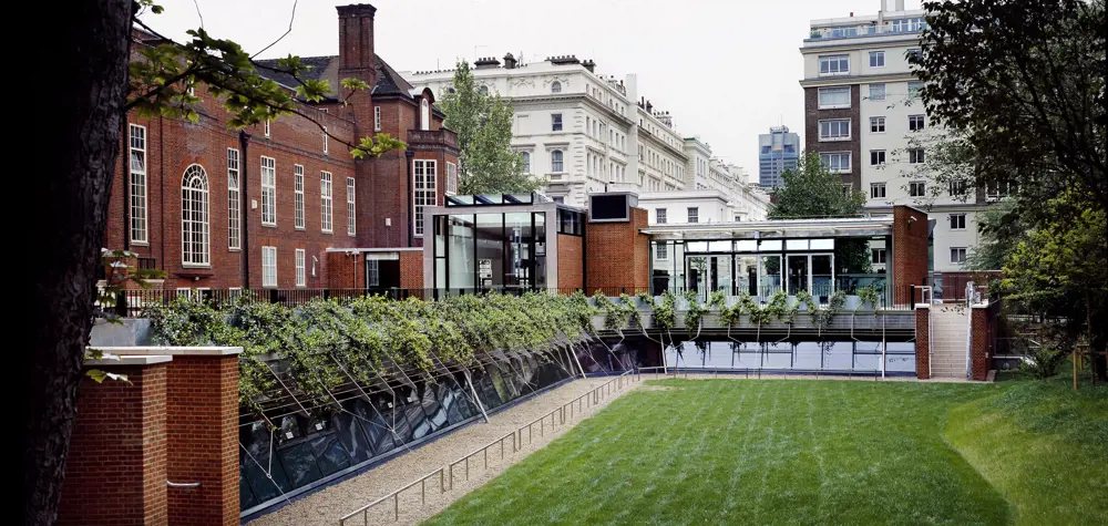 The outside of the building for the Royal Geographical Society in Kensington with a mowed lawn in front of the building. 