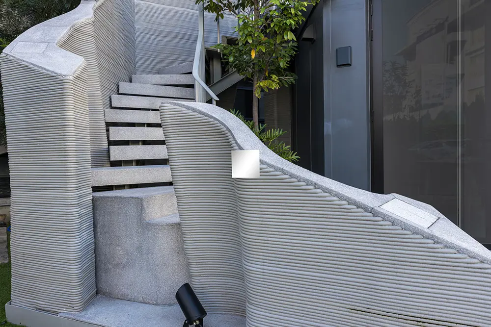 Curved 3D‑printed concrete staircase with layered walls forming an ornate architectural feature.