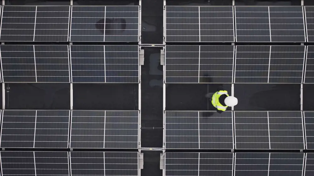 Aerial photo of a person walking in between solar panels on a roof