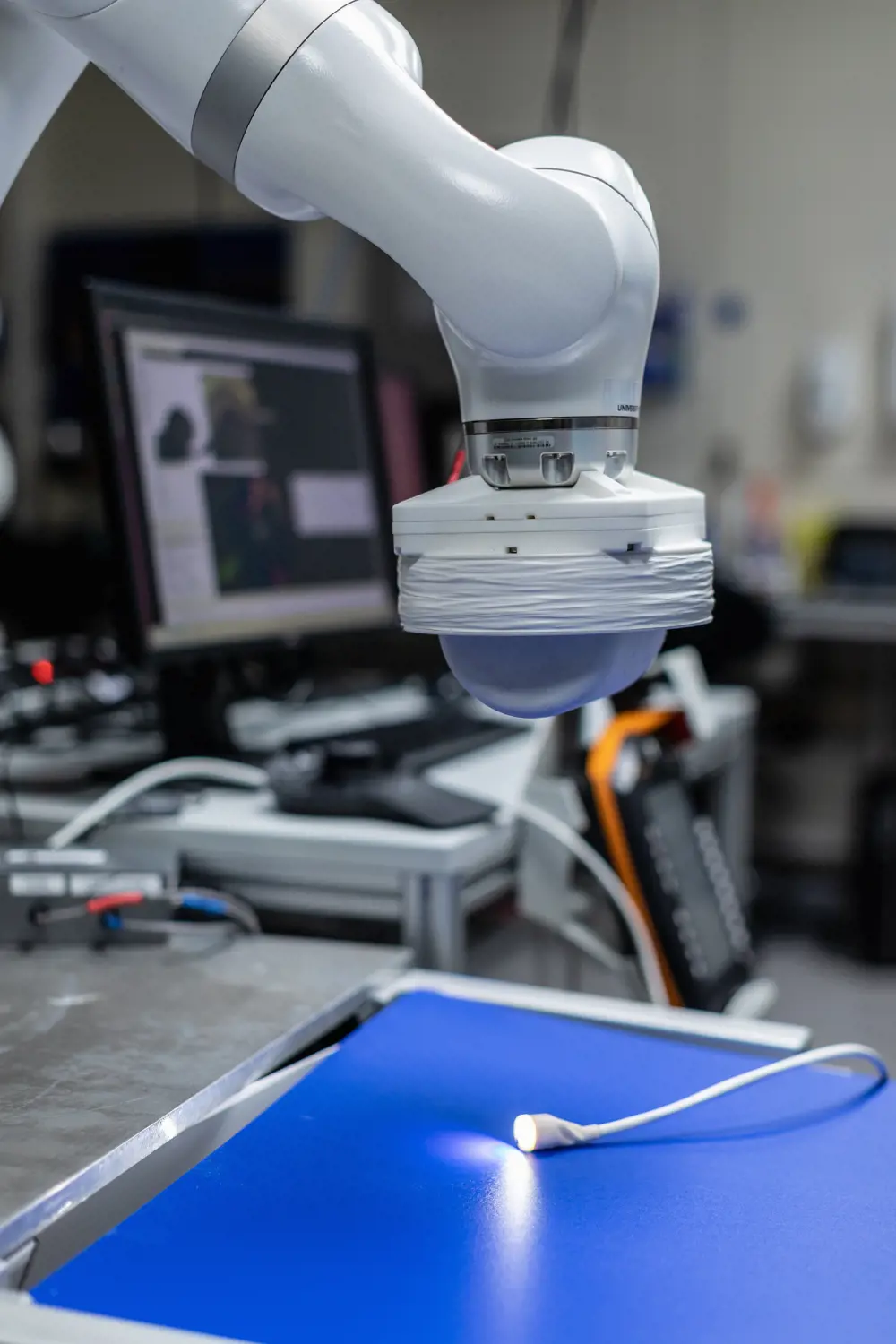 A magnetic robotic arm above a robotic colonoscope with a light on the end.