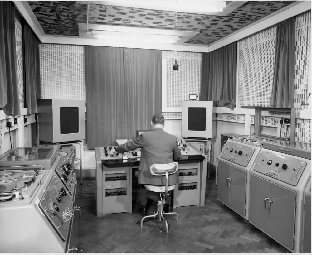 A greyscale image of the back of Gus Cook, working on BTR-3 tape machines in Abbey Road Studios.