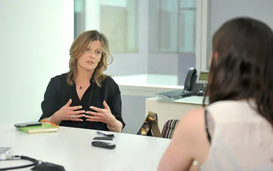 Jo da Silva sitting at a table, having a conversation with another person.