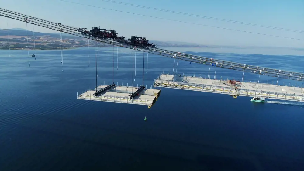 A tandem section of a bridge's deck being lifted into place.