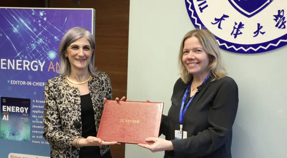 A photograph of two people holding a red plaque with the letters 'ELSEVIER' printed on in gold.