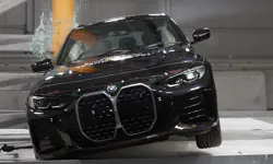 A BMW i4 crashing into a pole on its right hand side. The glass in the windows is shattering and the airbags have inflated.