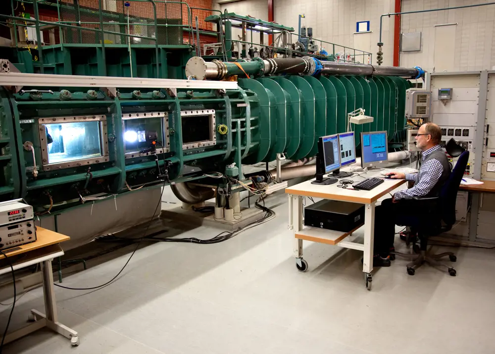 A person sitting on a chair in front of a computer in a room that contains cavitation tunnels.