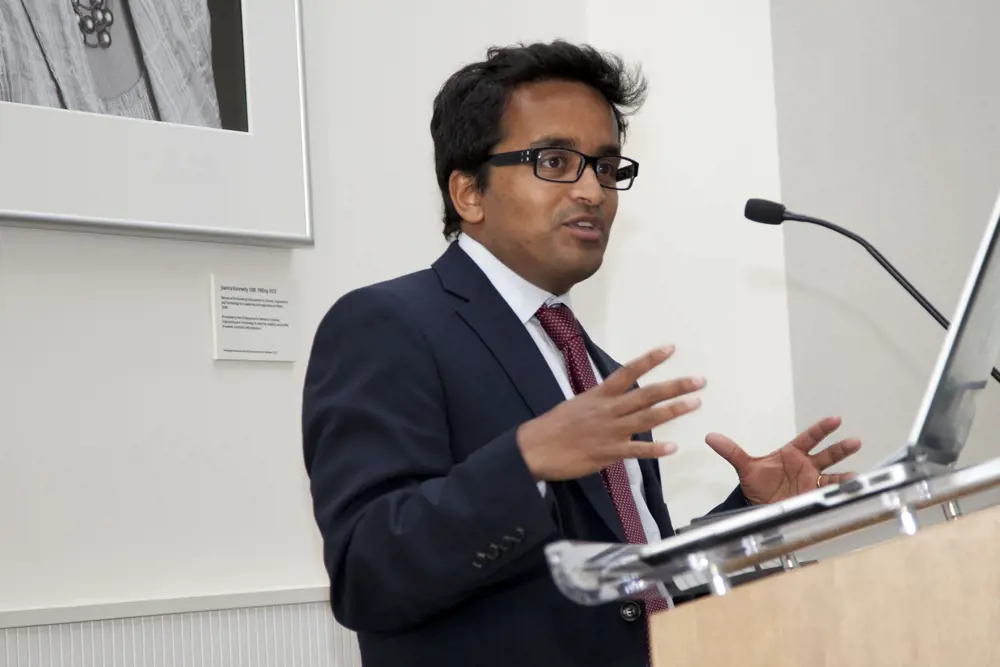 Suranga Chandratillake standing in front of a podium, giving a talk. 