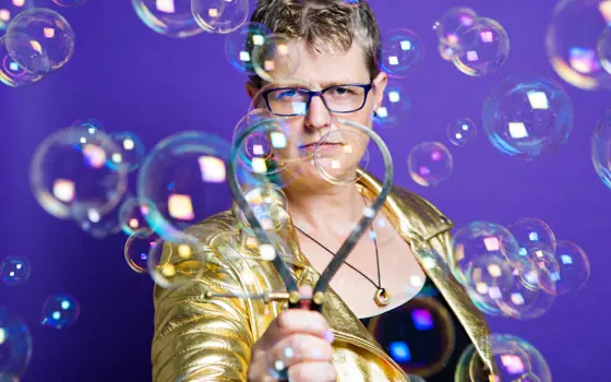 A photo of Lucy Rogers holding an engineered metal bubble maker, surrounded by bubbles