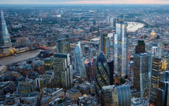 An aerial view of London's skyscraper buildings in the foreground with the River Thames behind them.