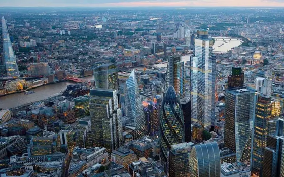 An aerial view of London's skyscraper buildings in the foreground with the River Thames behind them.