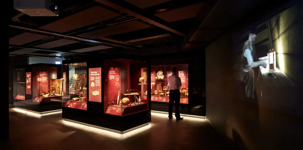 A person standing in front of museum display cases, looking at artefacts inside the Mary Rose museum.
