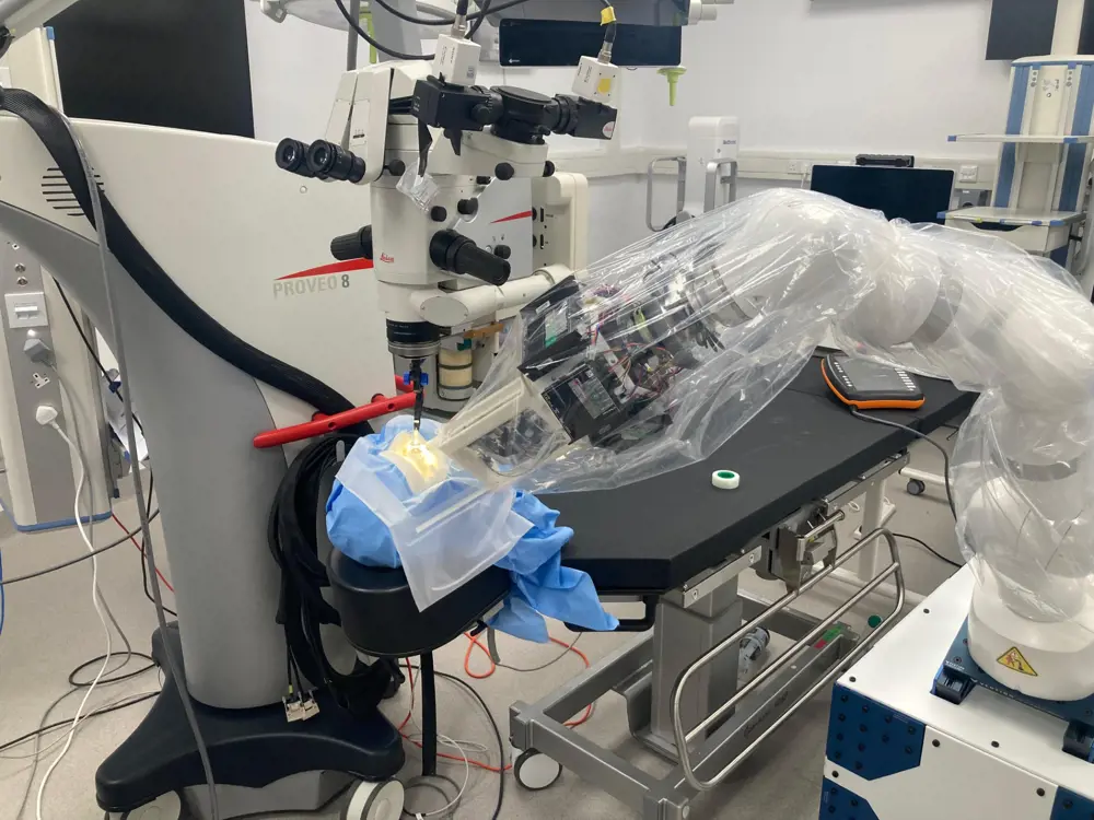 The surgical robot -- on a large grey robotic arm -- covered in a transparent plastic bag