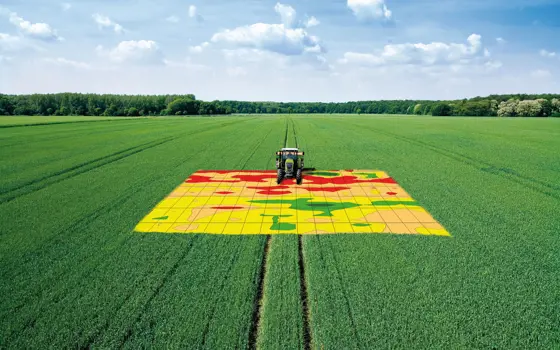 A tractor going over a digital map that has been projected onto a field.