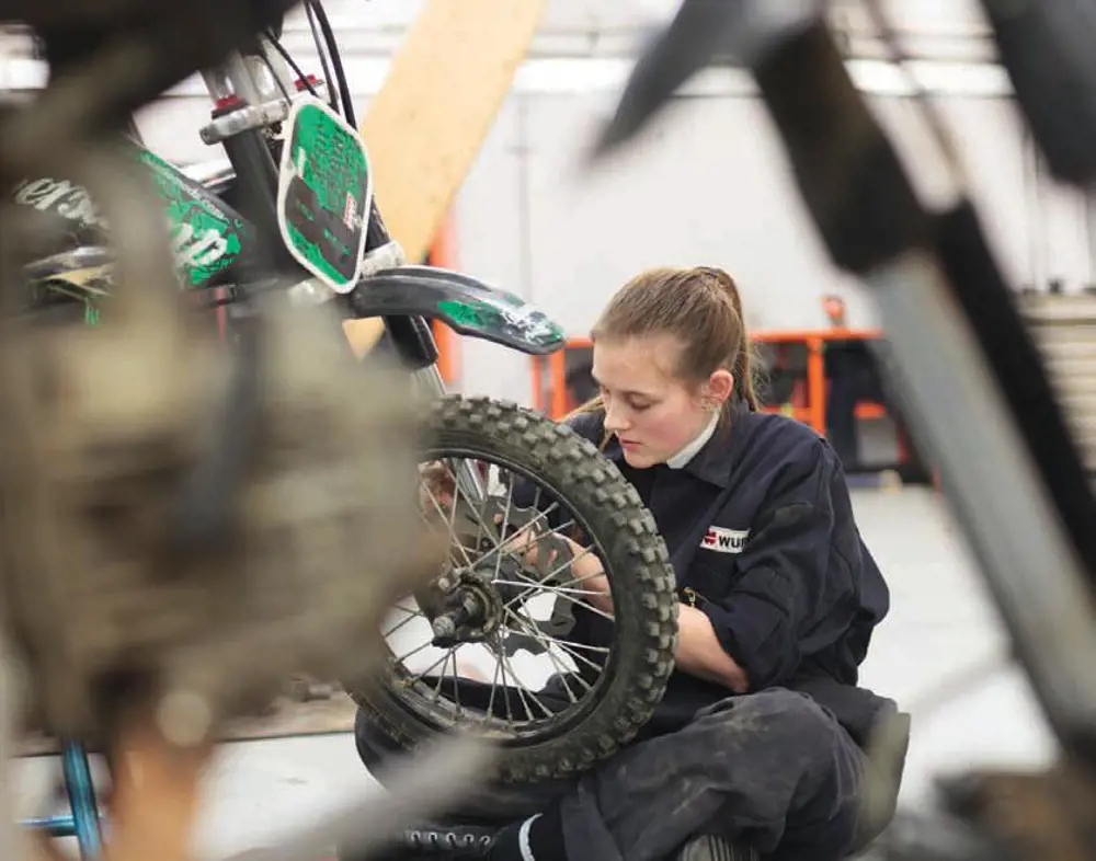 A young female fixing a motorbike.