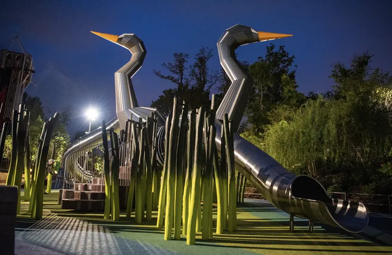 Two metal slides shaped like herons at night