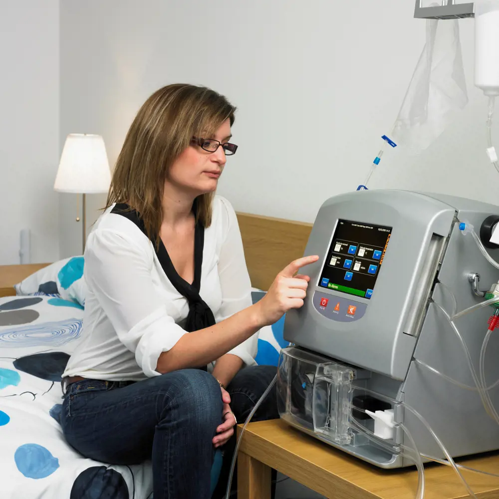 A woman touching the screen of the Quanta SC+ portable haemodialysis system. 