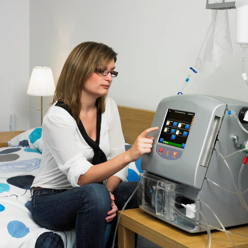 A woman touching the screen of the Quanta SC+ portable haemodialysis system.