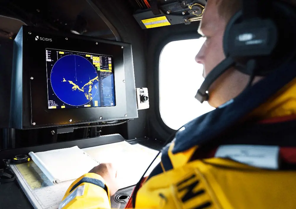A person wearing a headset, looking at a navigation radar screen inside a boat.