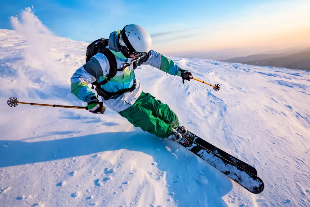 A skier leaning into the side of the mountain as they carve into the snow.