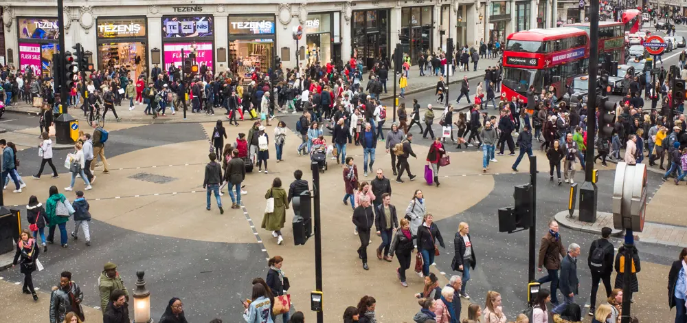 The diagonal crossing at Oxford Circus as pedestrians walk across it, with traffic waiting at the edge.