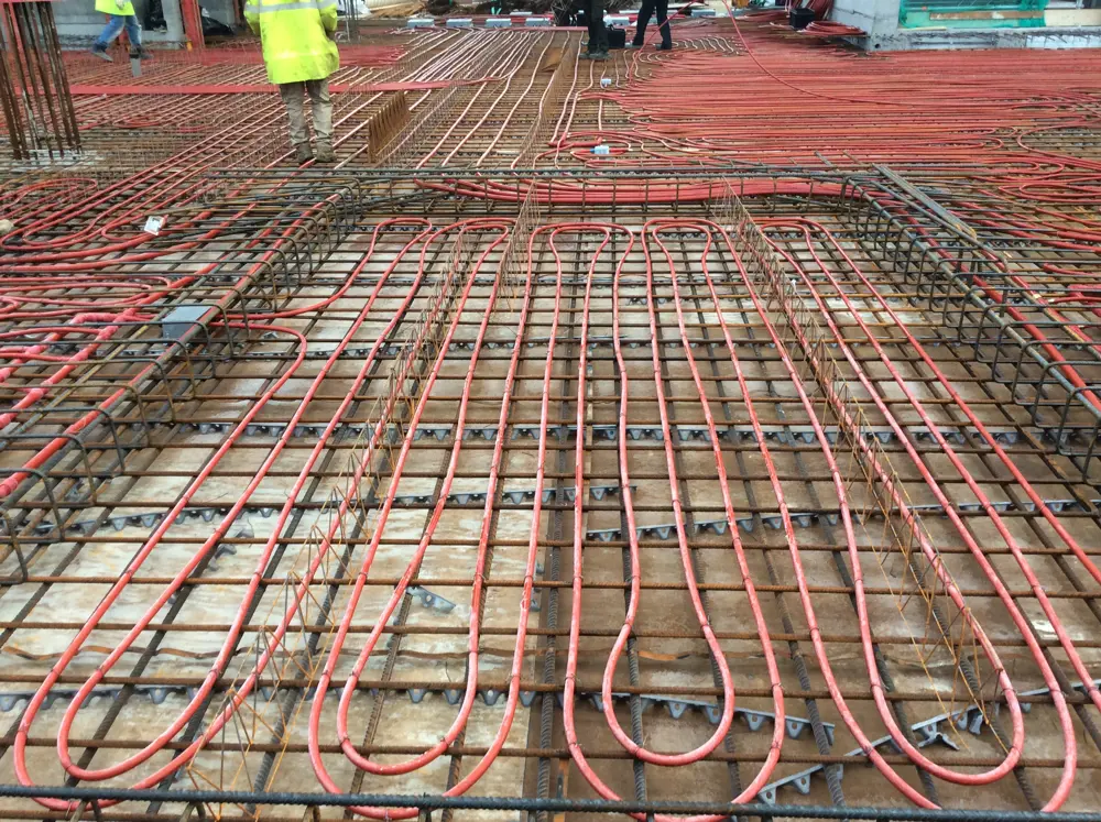Red pipes arranged inside concrete bars on the floor.