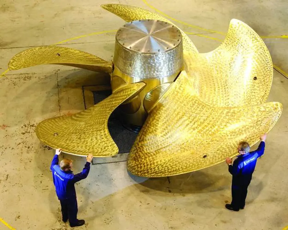 Workers standing next to propellers placed on the floor from the QE-class Aircraft carrier.