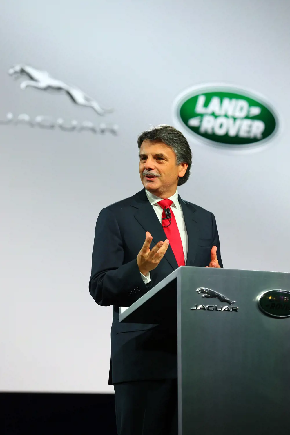 Dr Ralf Speth speaking at a podium for Jaguar Land Rover. 