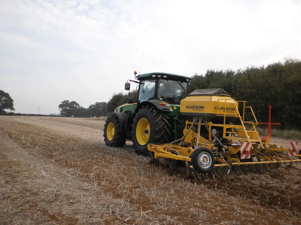 A photograph of a tractor in a field with a plough attached to the back of it.