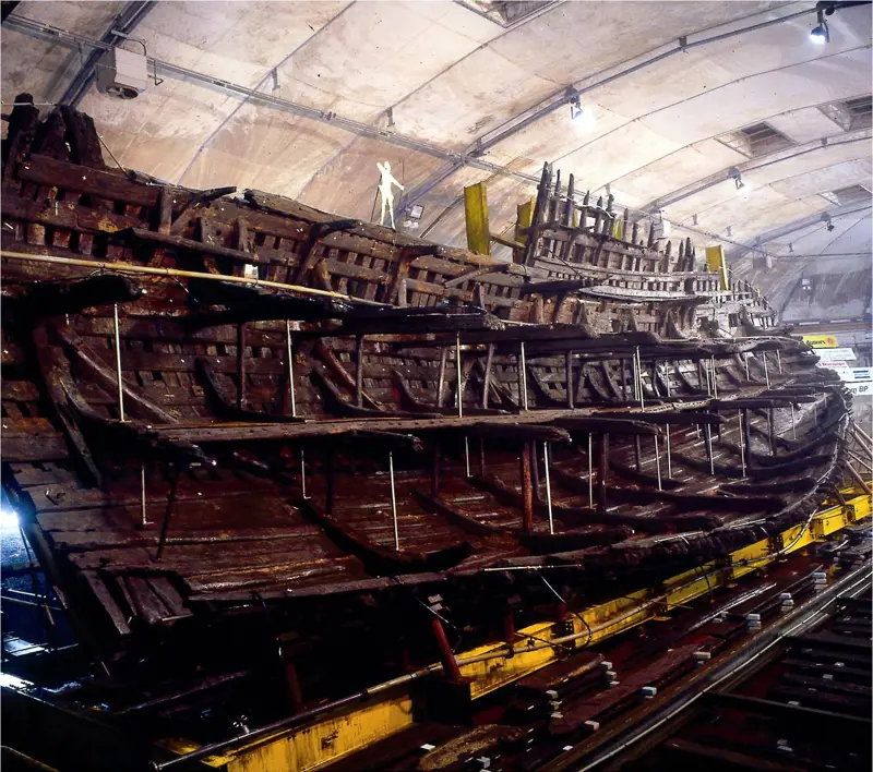 The wooden hull of the Mary Rose on a yellow cradle.