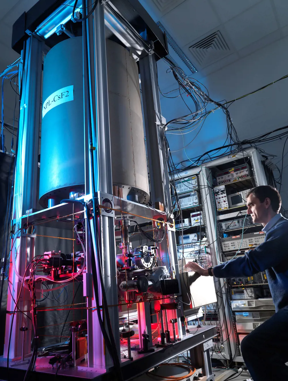 A person with the NPL CsF2 atomic clock in a room.