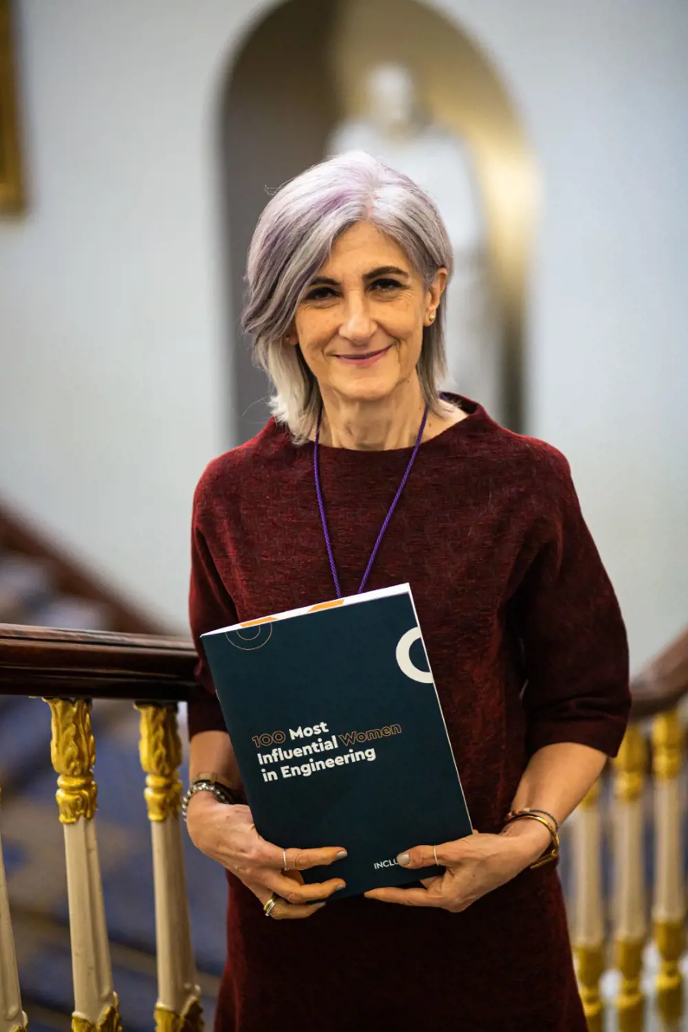 A photograph of Professor Ocone holding a book titled '100 Most Influential Women in Engineering'.