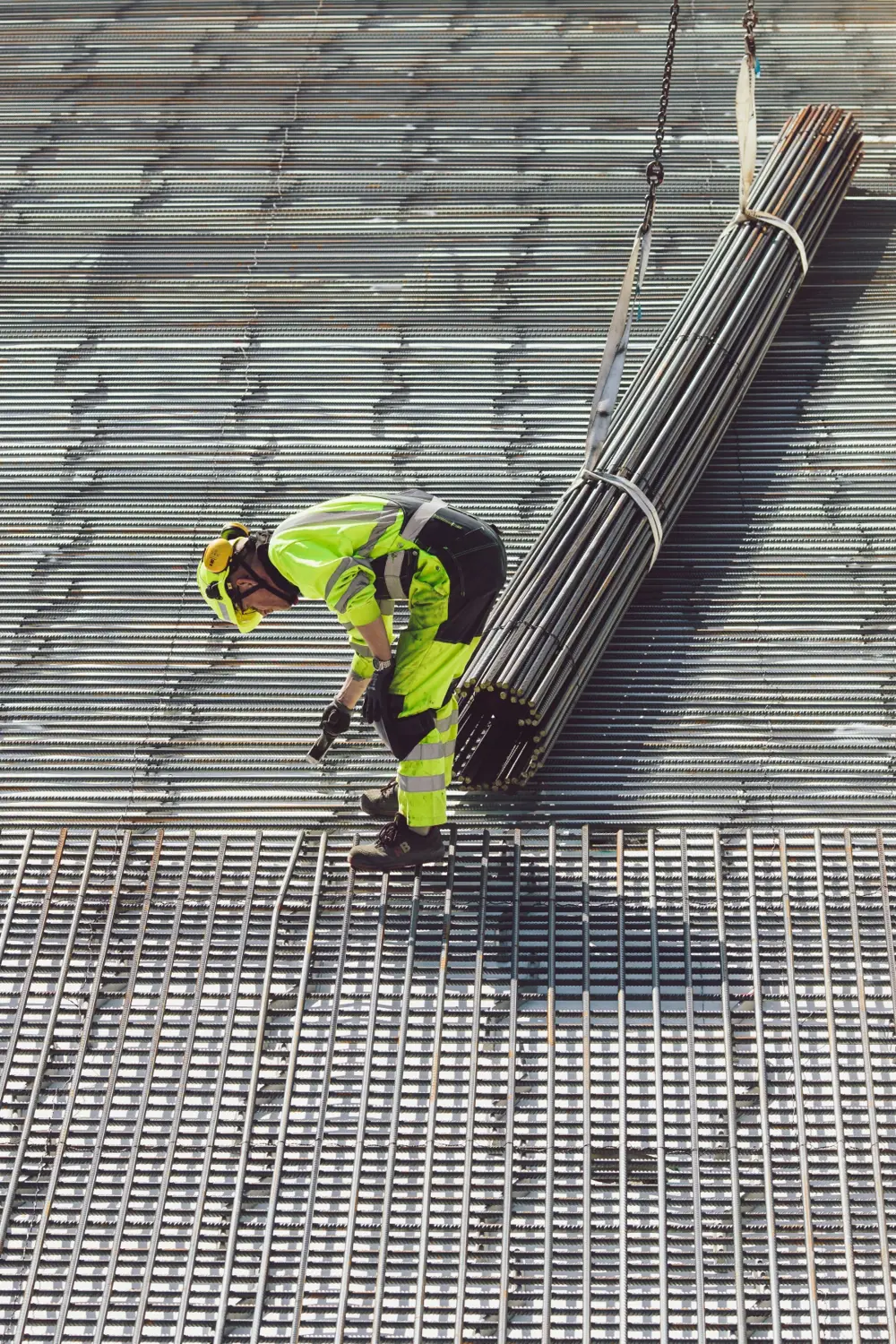 An engineer working with steel for a foundation, wearing a hard hat.