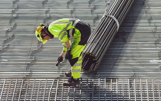 An engineer working with steel for a foundation, wearing a hard hat.