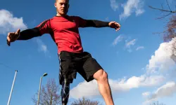 A male with a prosthetic leg wearing sports gear.