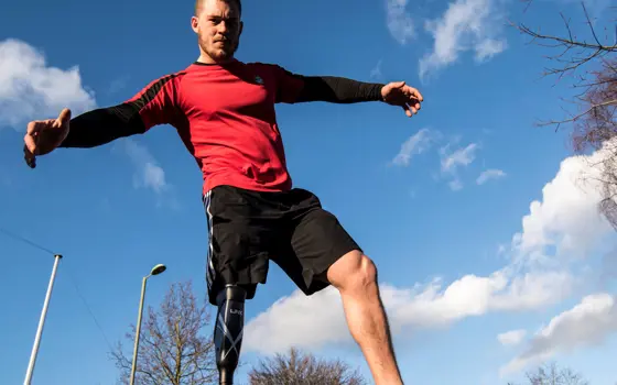 A male with a prosthetic leg wearing sports gear.